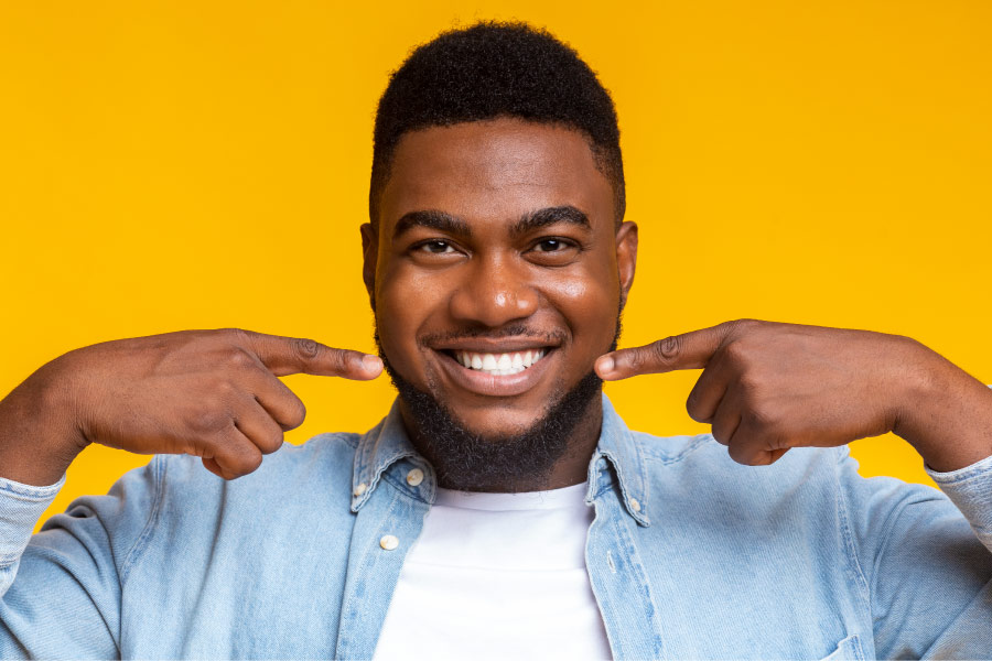 man in a denim jacket pointing at his smile