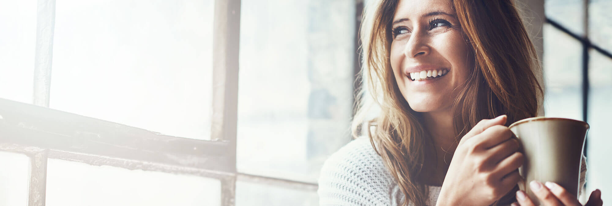 woman holding a coffee mug looking out a window