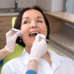 Brunette woman at the dentist gets her teeth cleaned and examined