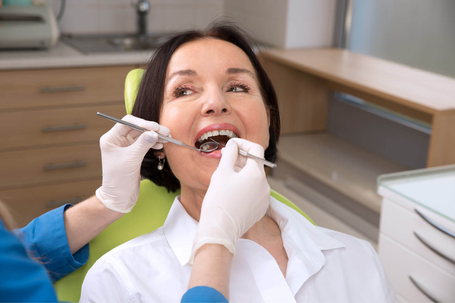 Brunette woman at the dentist gets her teeth cleaned and examined