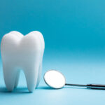 A tooth next to a special dental mirror against a blue background to symbolize a tooth extraction