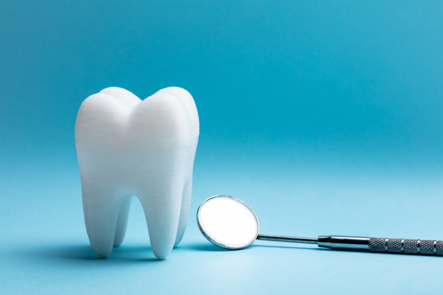 A tooth next to a special dental mirror against a blue background to symbolize a tooth extraction