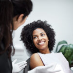 A curly-haired woman smiles with good oral health after a deep cleaning at the dentist