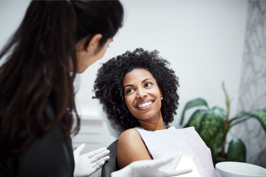 A curly-haired woman smiles with good oral health after a deep cleaning at the dentist