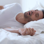 Man with obstructive sleep apnea snores while sleeping and needs a custom oral appliance