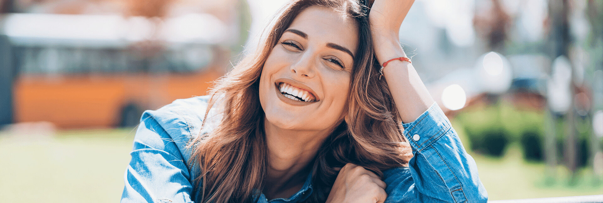 White woman with brown hair smiling outside after teeth whitening treatment.