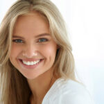 young blond woman flashes her white teeth in a smile