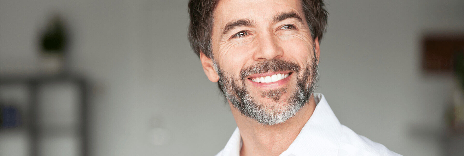 Older white man smiling after dental bridge procedure.