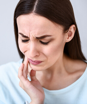 woman holding her jaw in pain