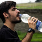 young man takes a drink from a big bottle of water