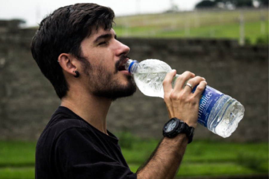 young man takes a drink from a big bottle of water