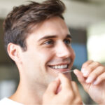 man smiles as he flosses his teeth