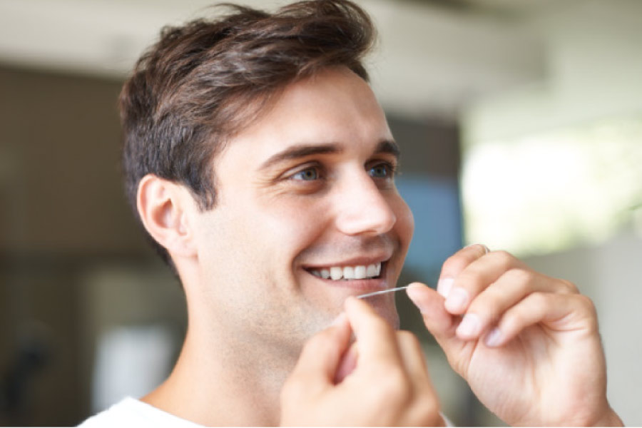 man smiles as he flosses his teeth