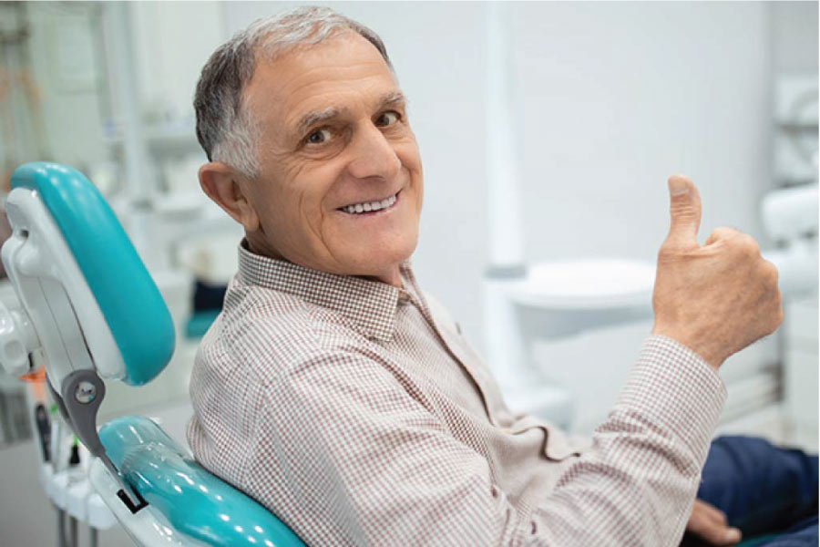 senior man gives a thumbs up in the dentist chair after a good checkup