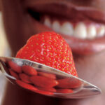 close up of a person about to eat a strawberry off a spoon