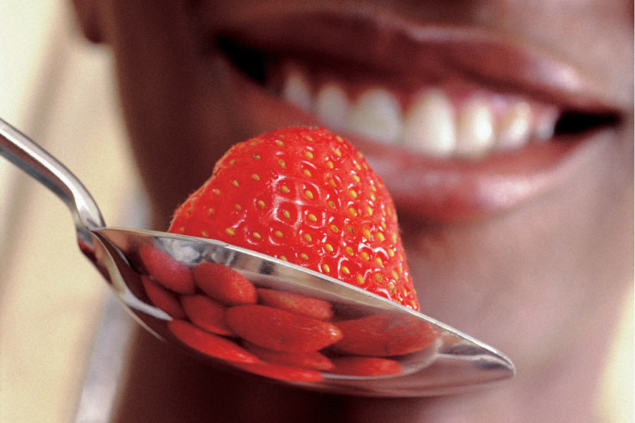 close up of a person about to eat a strawberry off a spoon